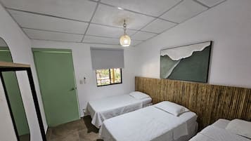 Une chambre d’hôtel avec deux lits simples, une fenêtre donnant sur un paysage agréable, un tableau au mur et un luminaire au plafond.