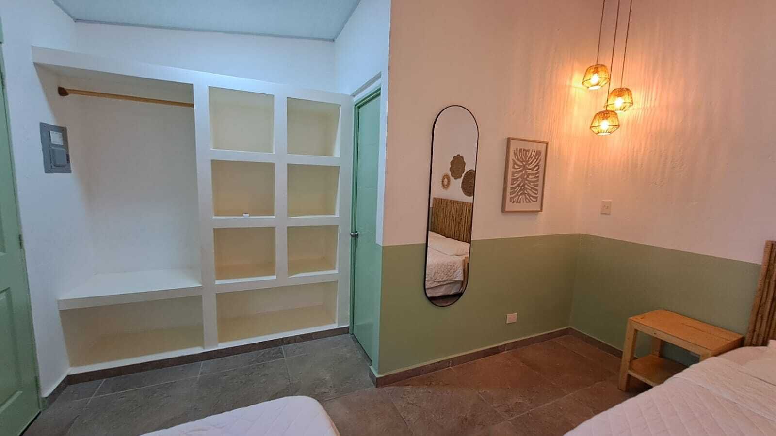 A bedroom with a bed, a wooden nightstand, a mirror, and a wardrobe with multiple compartments.