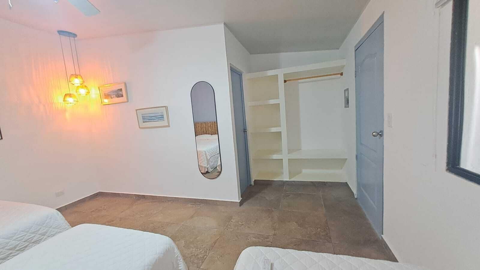 Une chambre d’hôtel avec deux lits, un miroir, une armoire et un petit coin salon.