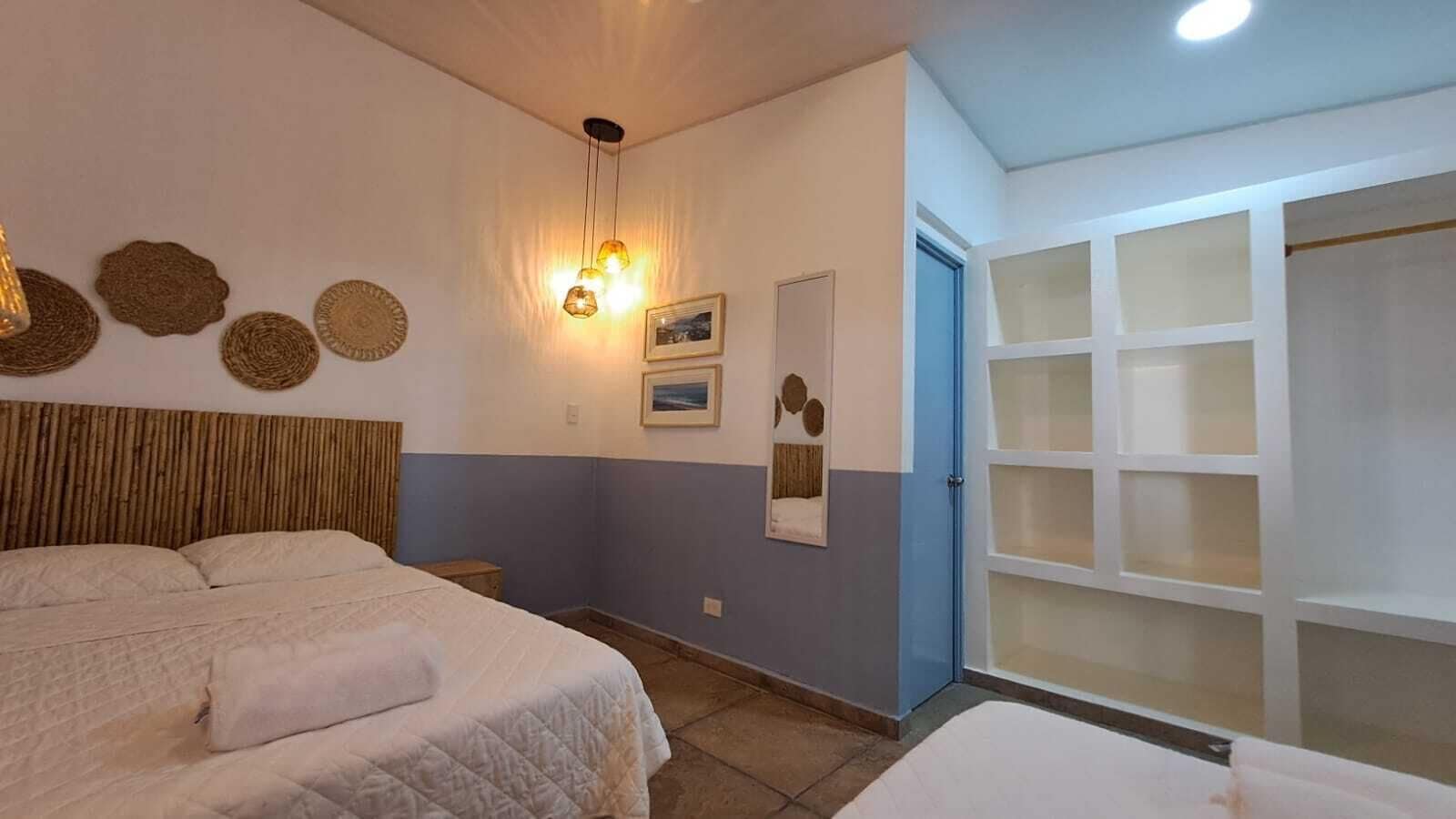 Quarto com cama, mesa de cabeceira, decoração na parede e guarda-roupa com várias prateleiras.