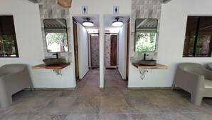 Ein Badezimmer mit zwei Waschbecken, jeweils mit Spiegel und Holzablage, sowie einem gefliesten Boden.