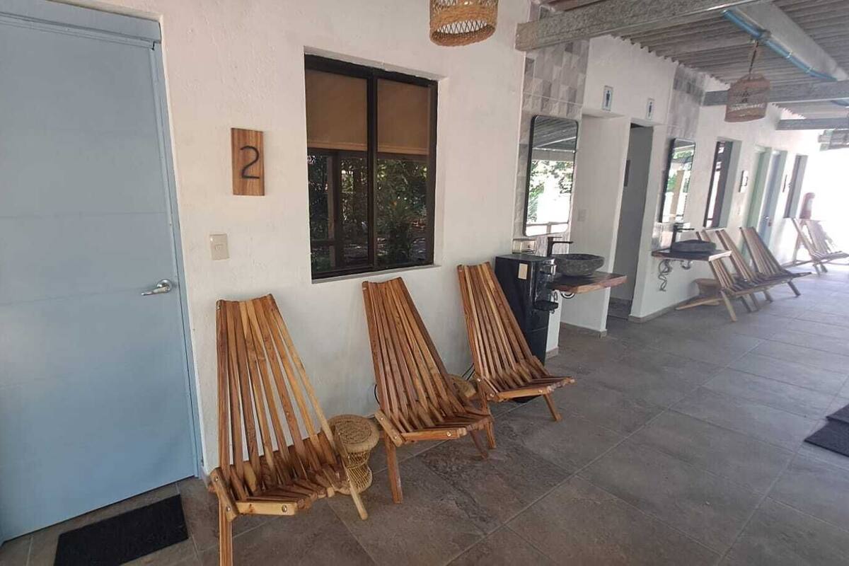 A covered outdoor seating area with wooden chairs and a window.