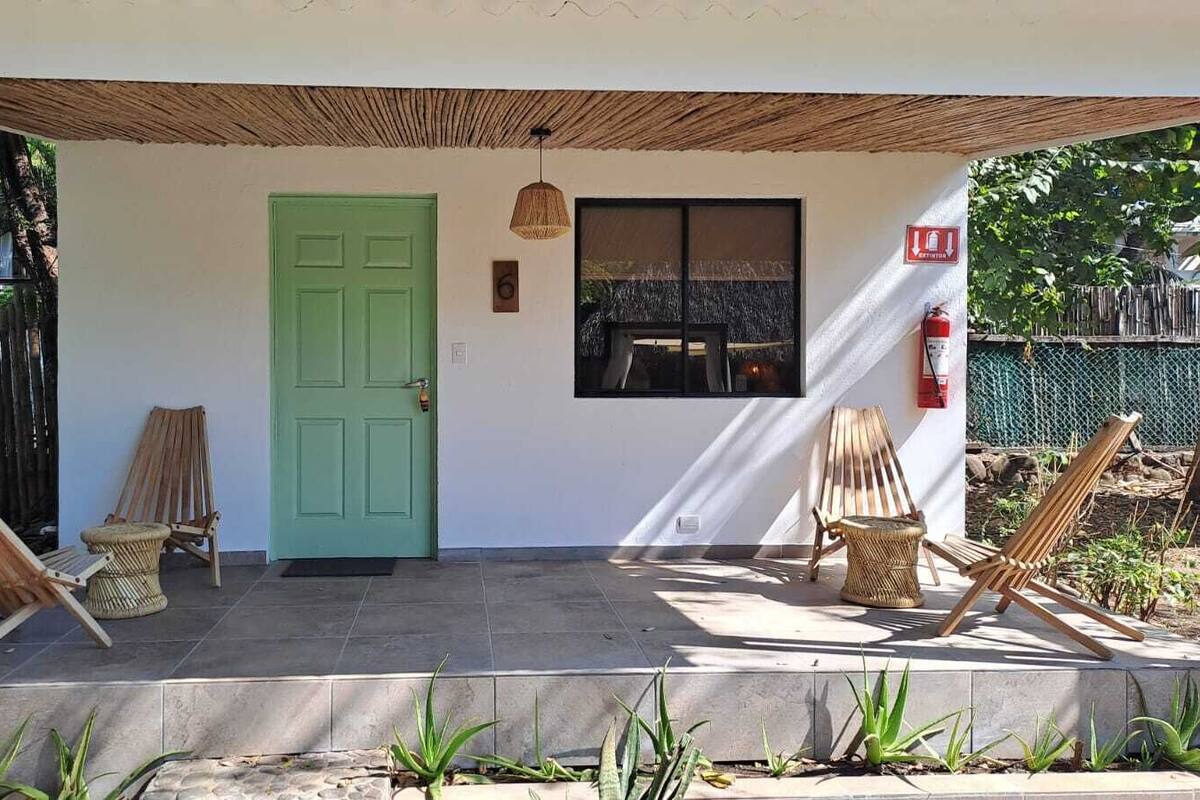 A covered porch with a green door, two wooden chairs, and a small table.