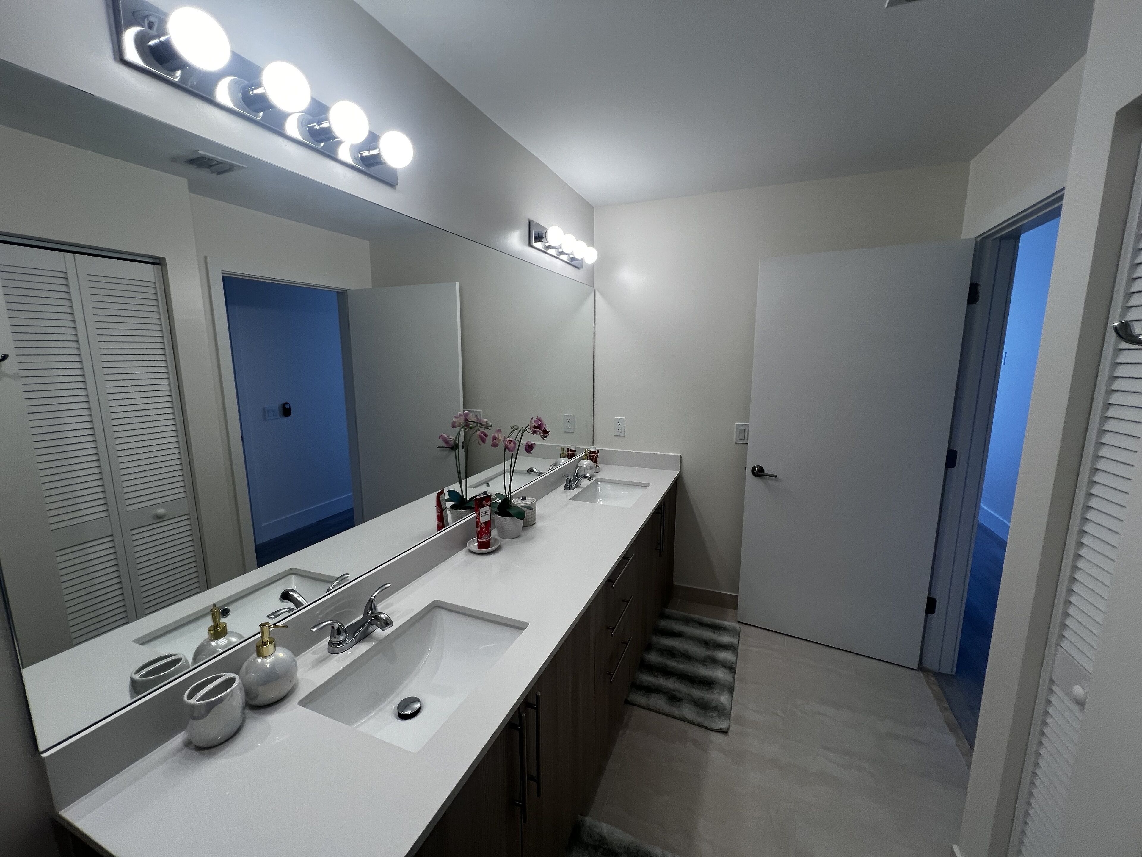 Un baño moderno con un espejo grande, dos lavamanos y un mueble de tocador.
