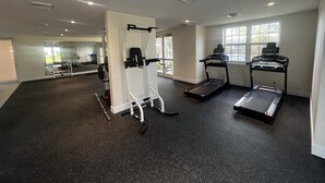 Ein Fitnessraum mit Laufbändern, einer Gewichtbank und einem Spiegel.
