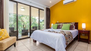 A hotel room with a bed, a bench, a nightstand, and a view of the outdoors.