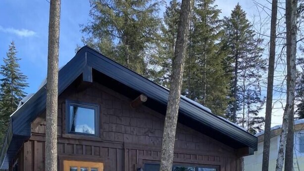 A wooden cabin with a deck, a front door, and large windows. - Aspen House, the "not so tiny" house! (Golden)