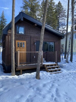 Surrounded by serene winter landscapes, this cabin offers a cozy retreat with a front door and expansive windows.