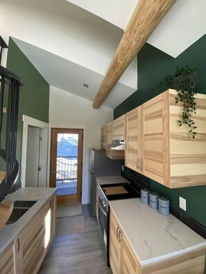 Enjoy cooking in this well-lit kitchen with a sink, stove, and ample cabinetry.