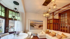 Una sala de estar moderna con un sofá blanco, una mesa de comedor redonda y un cuadro grande en la pared.
