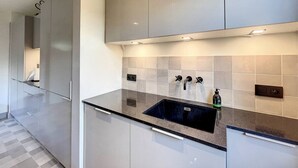 Eine moderne Küche mit dunkler Granitabdeckung, einer Edelstahlspüle und einem eingebauten Backofen.