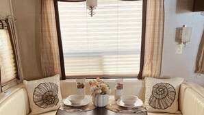 A cozy dining area with a round table, two beige cushioned benches, and a vase with flowers. - Book now! Special prices for the holidays and 2026 rentals! (Key Largo)