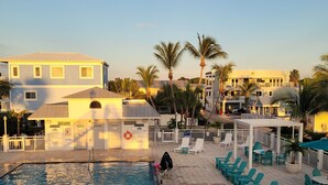 A swimming pool area with lounge chairs and a building in the background. - Book now! Special prices for the holidays and 2026 rentals! (Key Largo)