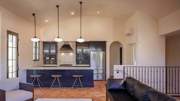A modern kitchen with a central island, bar stools, and pendant lighting.