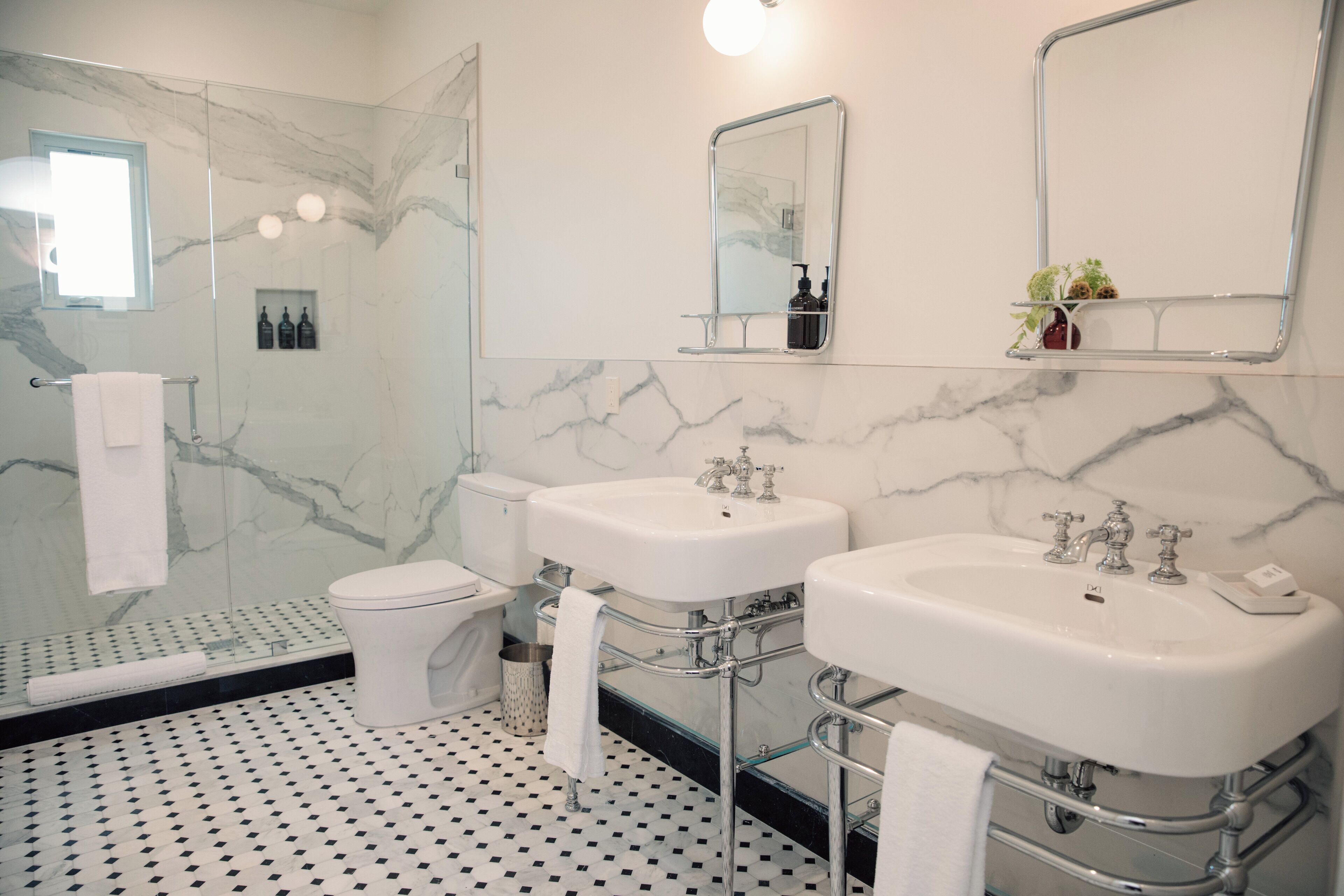 A modern bathroom with two sinks, a toilet, and a glass shower enclosure.