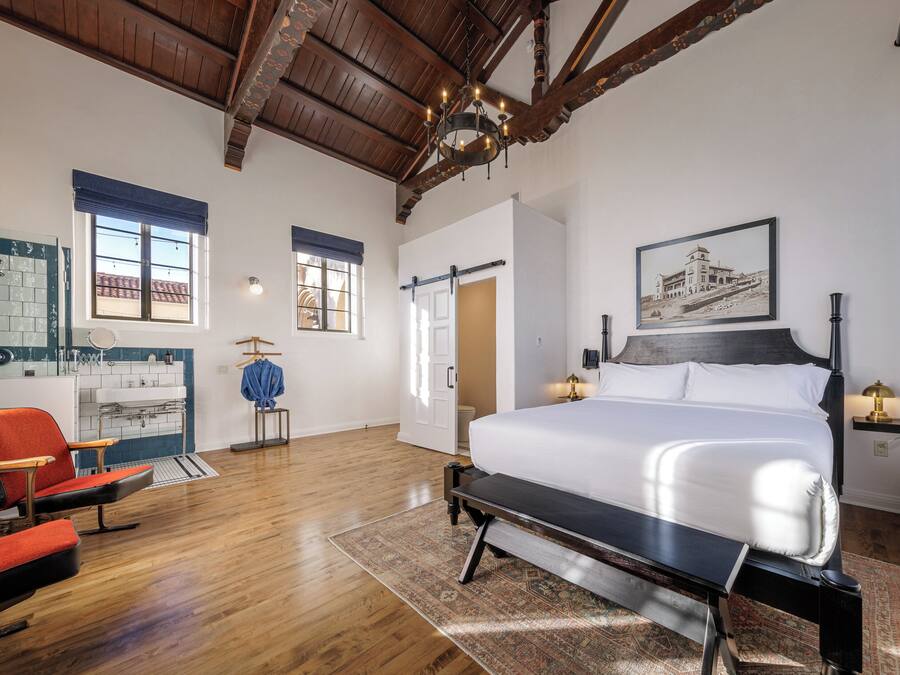 Um quarto espaçoso com uma cama grande, teto de madeira e vista para o exterior através de uma janela.