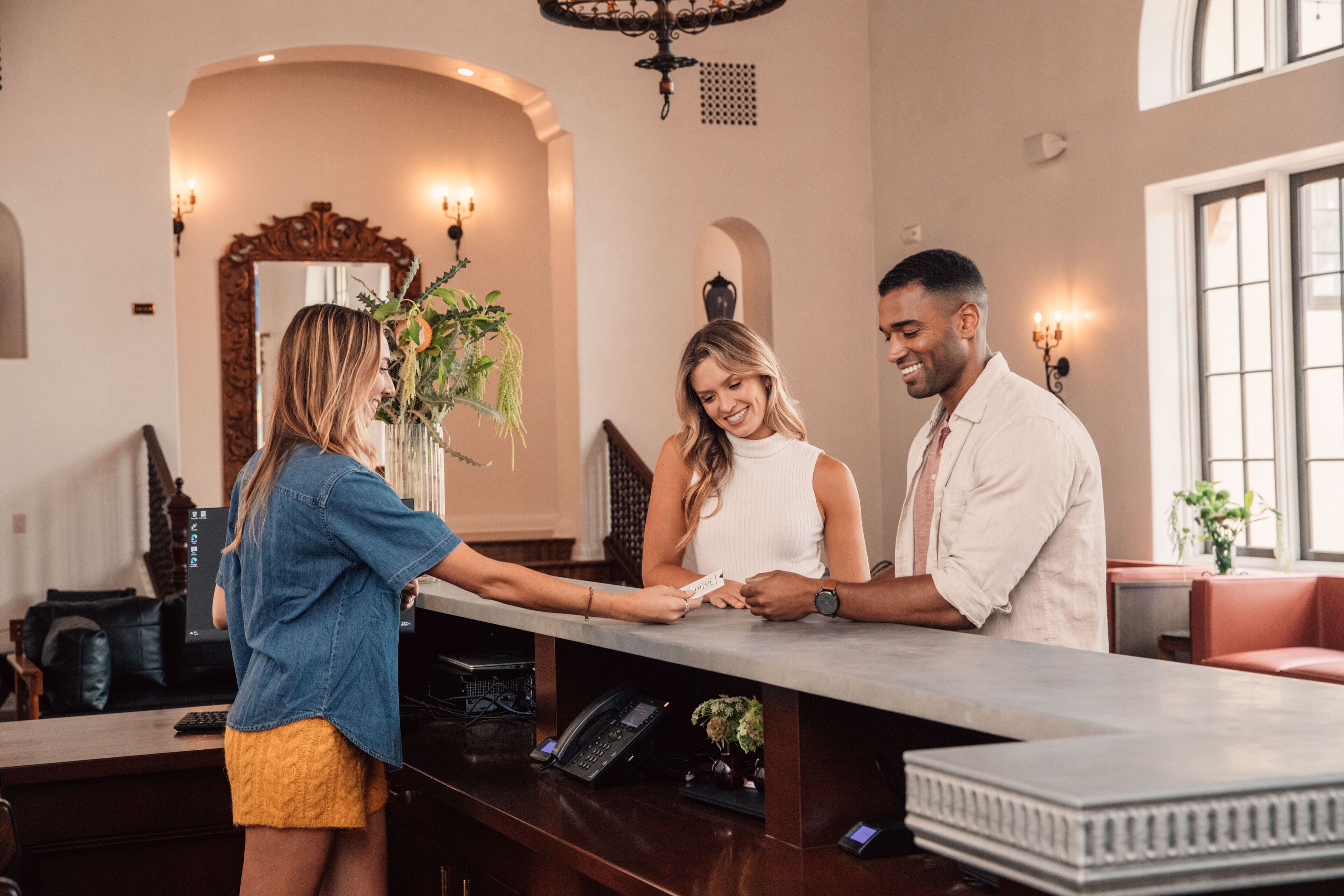 A reception area with a reception desk, a mirror, and a chandelier.