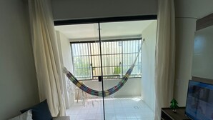 Una sala de estar con una hamaca, un sofá y un televisor.