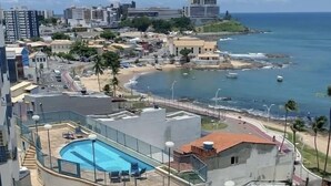 Zona de piscina en la azotea con vista al océano y al paisaje urbano.
