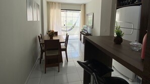 Una cocina compacta con zona de comedor, un refrigerador y una ventana con cortinas.
