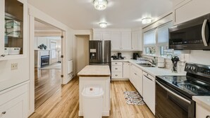 A modern kitchen with white cabinetry, stainless steel appliances, and a wooden island. - Prime Location walk to attractions w Free Parking (Seattle)