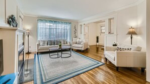 A spacious living room with a fireplace, two sofas, a coffee table, and a large window with blinds. - Prime Location walk to attractions w Free Parking (Seattle)