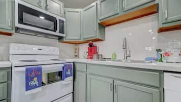 A kitchen with light green cabinets, a white stove, and a microwave.