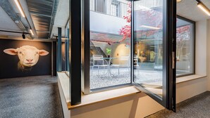 A modern interior with a large glass window, a sheep mural, and a staircase leading to an upper level. - Gasthaus Hof (Appenzell)