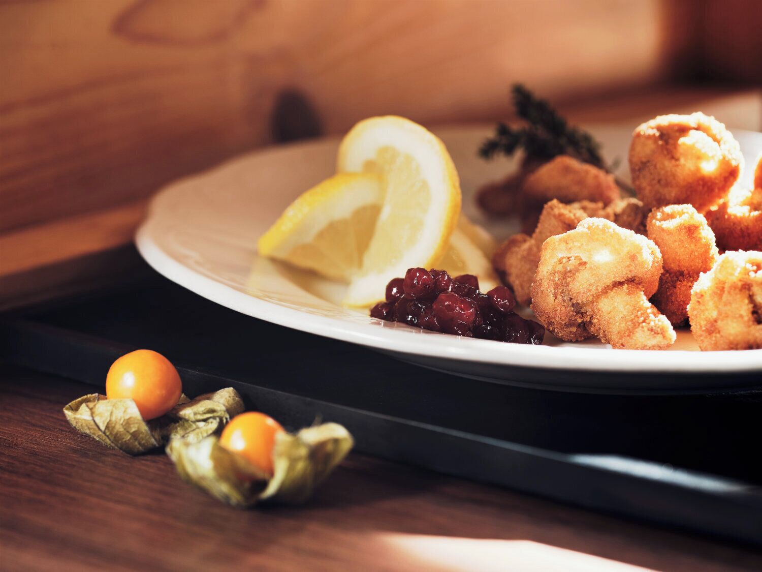 A plate with fried food, lemon slices, and berries.