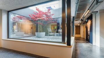 Ein moderner Innenraum mit großem Fenster, einem Blumentopf und einer Sitzecke.
