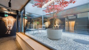 A modern interior with a glass partition, a potted tree, and a wall-mounted animal head. - Gasthaus Hof (Appenzell)