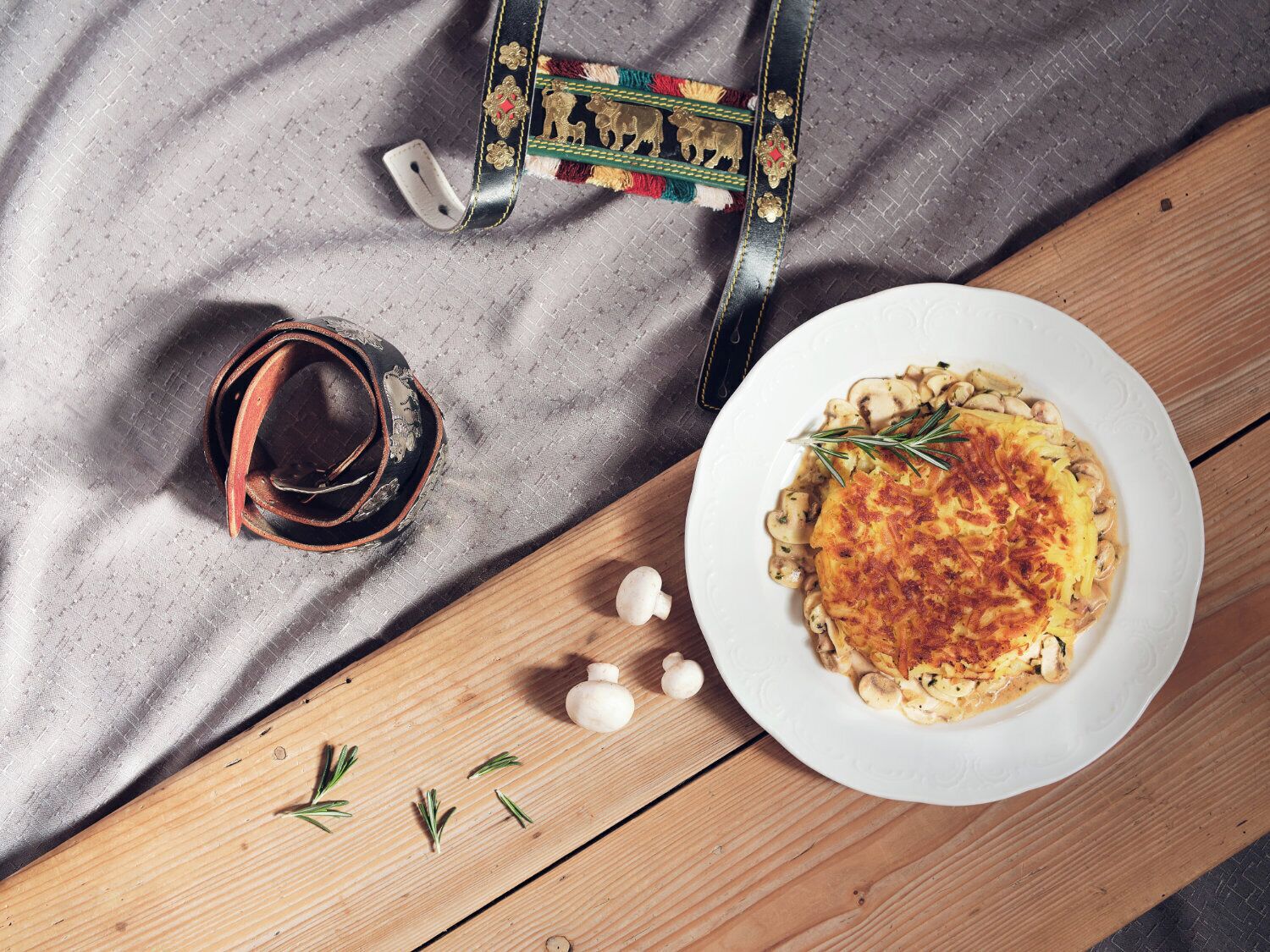 A plate of mushroom risotto with rosemary garnish on a wooden table.