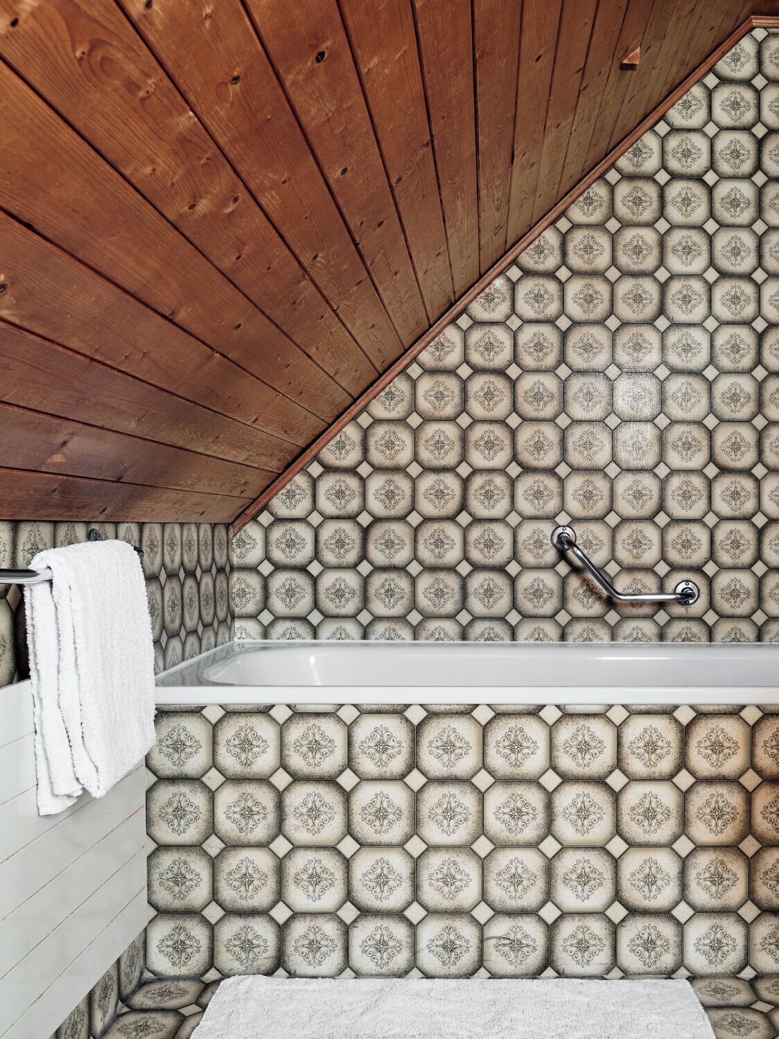 Un baño con techo de madera, una bañera y pared de azulejos estampados.