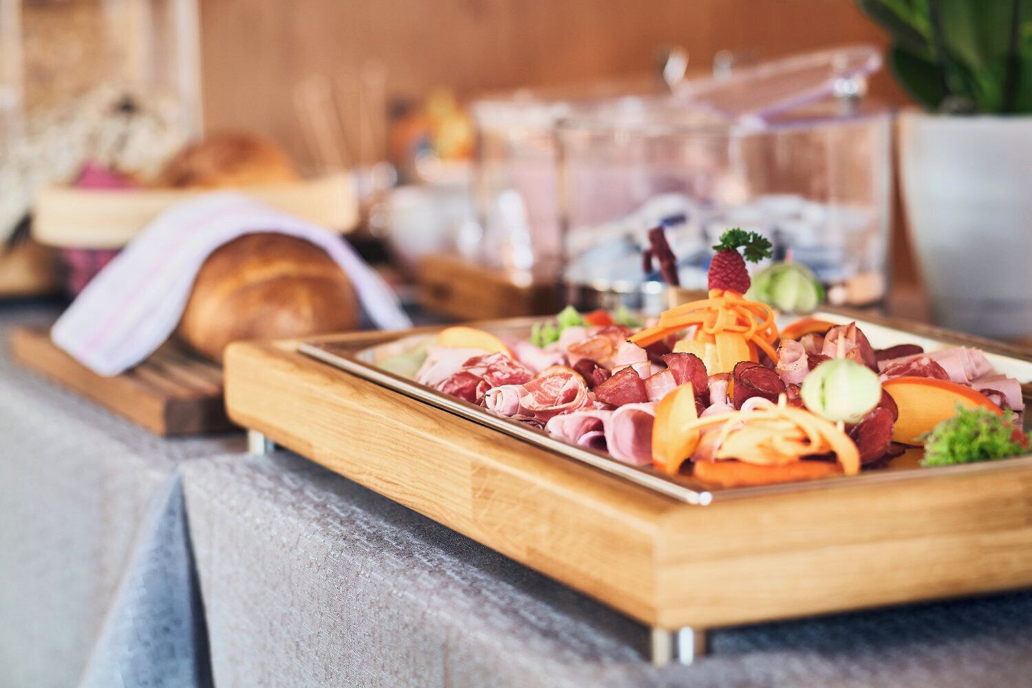 Ein Holztablett mit verschiedenen Fleisch- und Gemüsesorten auf einem Tisch.