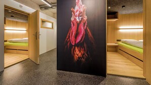 A modern hotel room with a large painting of a rooster, wooden furniture, and built-in lighting. - Gasthaus Hof (Appenzell)