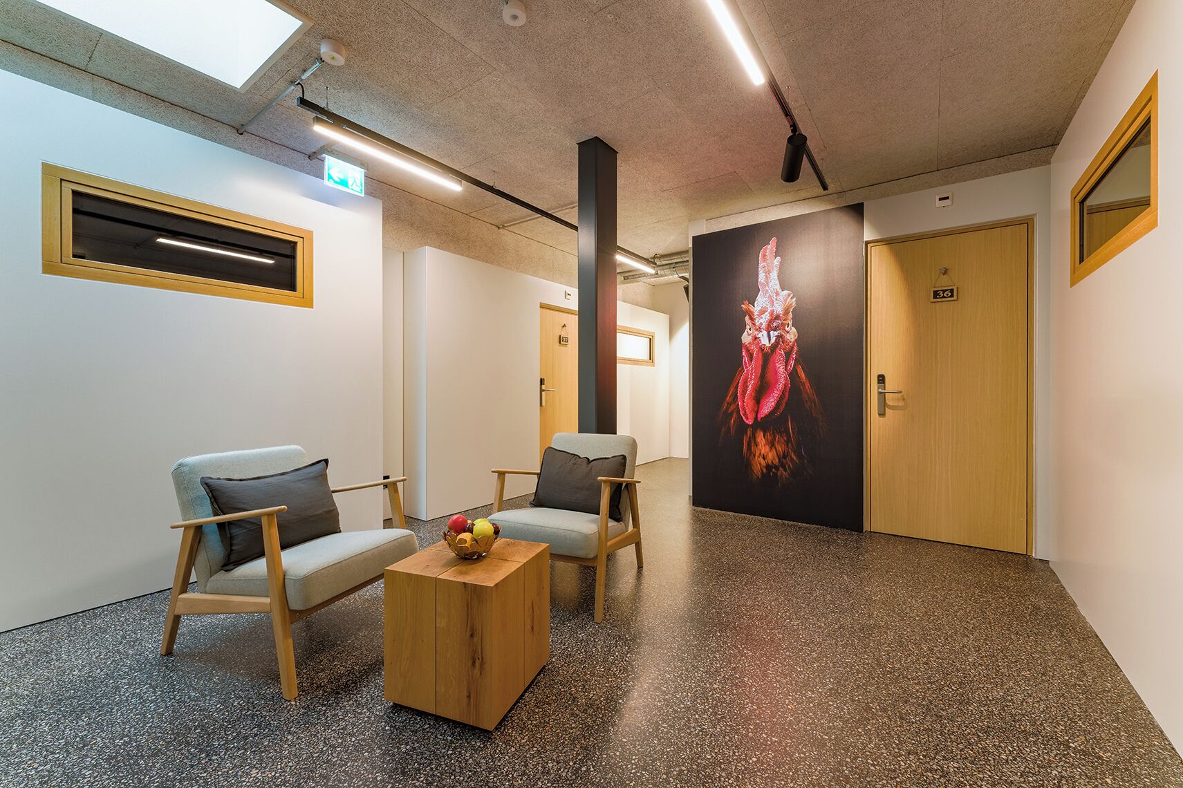 Une salle d’attente avec deux chaises, une table basse et une grande affiche accrochée au mur.