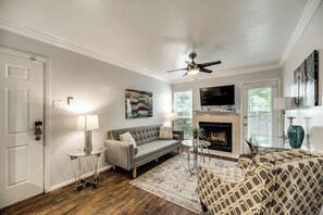 A living room with a sofa, a coffee table, a fireplace, and a television. - I28 - Apt|Patio|10mi to Convention Ctr|Sleeps 2 (Irving)