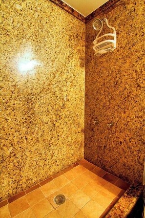 A shower area with a granite wall and a showerhead. - I28 - Apt|Patio|10mi to Convention Ctr|Sleeps 2 (Irving)