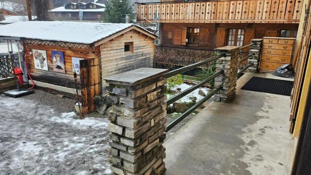 Un edifici de fusta amb una escala de pedra i una petita construcció de fusta amb obres d'art.