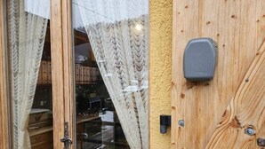 Una porta de fusta amb un panell de vidre i un petit dispositiu electrònic muntat al damunt.