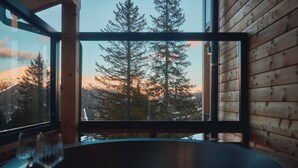 Una habitación con un ventanal grande que ofrece vistas a árboles altos y una cadena montañosa.
