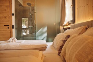 Un dormitorio con una cama grande, un armario de madera y cabina de ducha de vidrio.