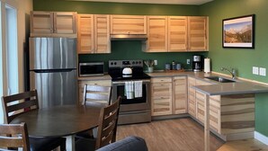 Una cocina moderna con armarios de madera, electrodomésticos de acero inoxidable y una pared verde.