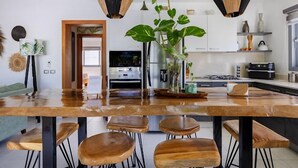 A modern kitchen with a large wooden island, black hanging pendant lights, and a potted plant. - Charming, luxurious 2 bedroom apt.  in amazing Las Terrenas with WiFi, AC.  (Las Terrenas)