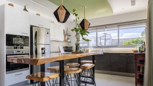A modern kitchen with white cabinets, a wooden bar counter, and a view of the city through large windows. - Charming, luxurious 2 bedroom apt.  in amazing Las Terrenas with WiFi, AC.  (Las Terrenas)