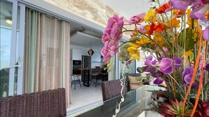 A modern interior with a glass table, wicker furniture, and a variety of colorful flowers. - Charming, luxurious 2 bedroom apt.  in amazing Las Terrenas with WiFi, AC.  (Las Terrenas)
