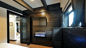 Un dormitorio con cama, chimenea, armario y puerta que da a otra habitación.