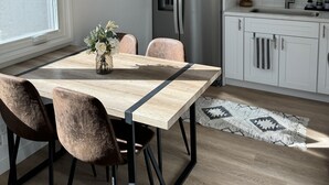 A modern kitchen with a built-in refrigerator, white cabinetry, and a dining area with a wooden table and chairs. - Sandyland Beach Studio Carpinteria (Carpinteria)