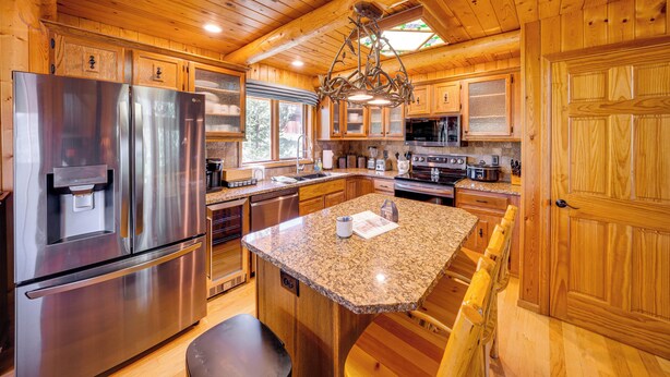 A spacious kitchen with wooden cabinetry, stainless steel appliances, and a granite countertop island. - Lake & Mtn Views: Spectacular Grand Lake Home (Grand Lake)