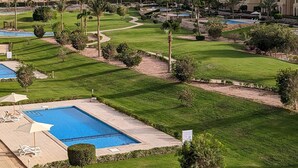 Un resort con varias piscinas, césped impecable y palmeras.